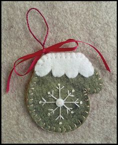 a green ornament with snowflakes and red ribbon hanging on the wall