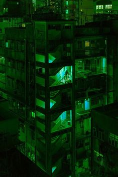 an aerial view of buildings at night with green lights in the building's windows