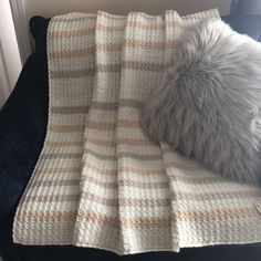 a blanket that is laying on top of a couch next to a pillow and pillows