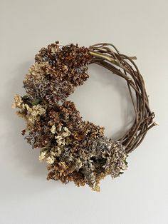 dried flowers are arranged in a wreath on the wall