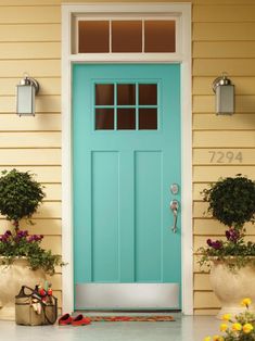 a blue front door with the words transom painted on it and flowers in pots next to it