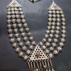 * This long, rusty silver necklace is embellished with fine floral elements, assembled in strings, making it one piece. The pendant is adorned with antique stone, dangling tassels, and floral motifs carved within the piece. This exclusive piece is an inspired style by Afghani kuchi ornaments, worn by the women of tribes as integral part of their cultural practices. You can pair this necklace with any traditional or trendy outfit, and it would get along any of the chosen fashion statements. Note: Bohemian Long Temple Necklace For Wedding, Bohemian Necklaces With Intricate Design For Festivals, Bohemian Long Temple Necklace For Festivals, Bohemian Long Bridal Necklace For Festivals, Bohemian Handmade Bridal Necklace For Festivals, Bohemian Bridal Necklace For Festivals, Bohemian Necklaces With Traditional Patterns For Festivals, Bohemian Necklace With Traditional Patterns As Gift, Bohemian Necklace With Traditional Patterns For Gift