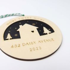 a wooden ornament with a house and trees on it