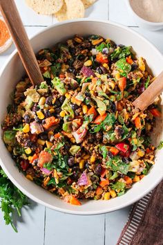 a white bowl filled with mexican salad and tortilla chips on top of a table