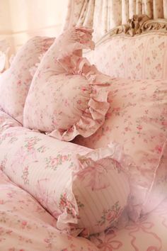 a bed with pink flowers and ruffled pillows