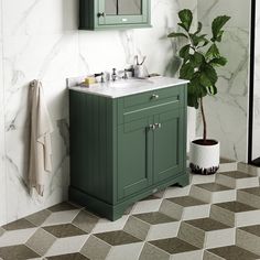 a bathroom with green cabinets and white marble counter tops, tile flooring and a potted plant