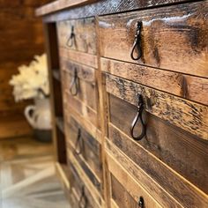 an old wooden dresser with black handles and some scissors hanging on the handlebars