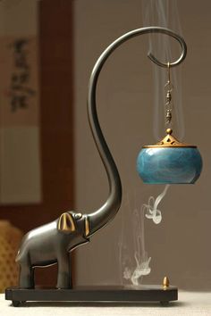 an elephant figurine with a tea light in it's trunk and a lamp hanging from the back