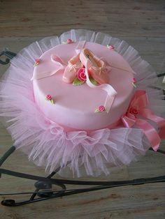 a pink cake decorated with ballet shoes and tulle