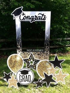 graduation decorations are placed in the grass near a mirror and sign that says congrats