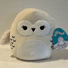 a white stuffed animal with black eyes and an owl tag