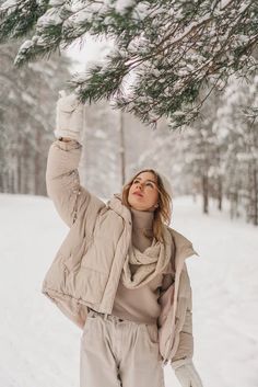 a woman standing in the snow holding onto a tree