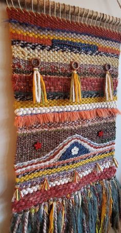 a multicolored wall hanging with tassels on it's sides and buttons in the middle