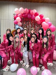 a group of women in pink pajamas posing for a photo with balloons and confetti