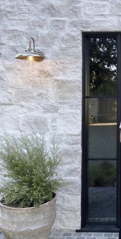 a man standing in front of a white brick building with a black door and window