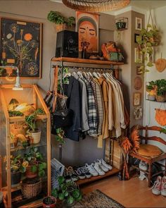 a room filled with lots of plants and clothes hanging on the wall next to a cat