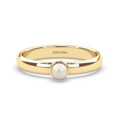 a yellow gold ring with a white pearl in the center and an inscription on it