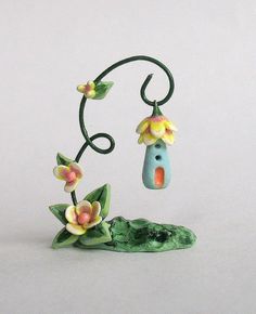 a small birdhouse with flowers hanging from it's side on a tree branch