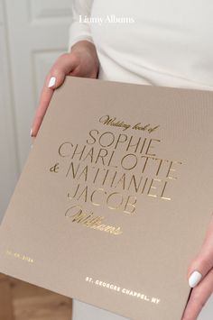 a woman holding up a book with gold foil lettering on it's front cover