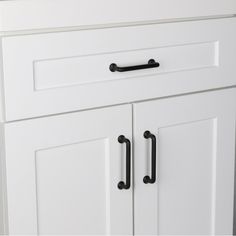 a white cabinet with two black handles on it