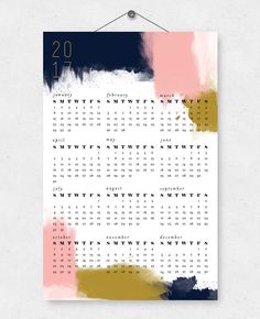 a calendar hanging on a wall next to a white wall with pink, blue and yellow paint