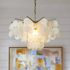 a chandelier hanging from the ceiling in a room with paintings on the wall