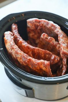 several pieces of cooked meat in a crock pot on a counter top, ready to be cooked