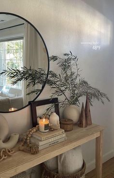 a mirror sitting on top of a wooden table next to a vase filled with plants