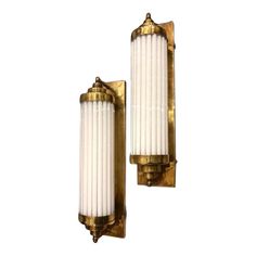 two brass sconces with white candles on them