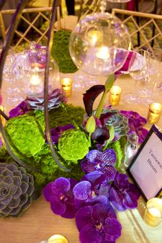 the centerpieces on this table are filled with purple and green flowers