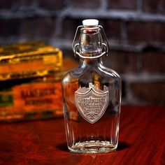 an empty glass bottle sitting on top of a wooden table next to some gold boxes