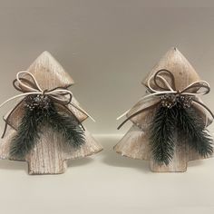 two small wooden christmas trees with bows and pine cones on them, one is made out of wood