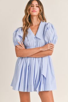 Add a touch of sophistication to your wardrobe with this Pinstripe dress. The short puff sleeves and v-neck collar create a classic look, while the self-tie and button front add unique details. Lined for comfort and in a beautiful blue color, this dress is perfect for any occasion. Bach Brunch, Farewell Brunch, Gameday Fits, Label Ideas, Pinstripe Dress, Church Dresses, Grad Dresses, Stripe Dress, Puffed Sleeves Dress