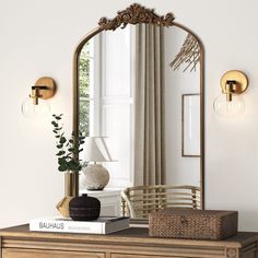 a mirror sitting on top of a wooden dresser next to a plant in a vase