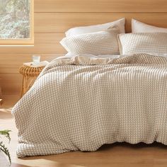 a bed with two pillows on top of it next to a table and chair in front of a window