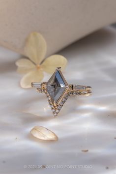 a diamond ring sitting on top of a white table next to a flower and shell