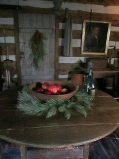 a wooden table topped with apples under a painting