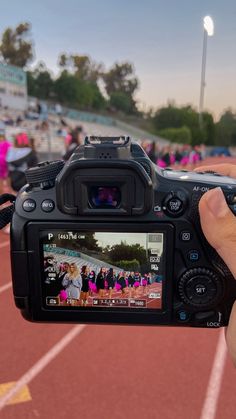 a person is holding up a camera to take a photo on the stadium's track