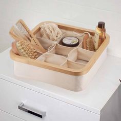 a wooden tray with various items in it on top of a white dresser next to a drawer