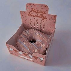 a pink donut with white frosting and sprinkles in a box