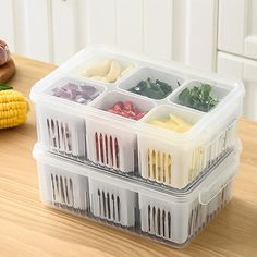 plastic containers filled with food on top of a wooden table next to vegetables and corn