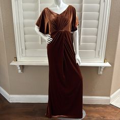 a mannequin wearing a brown dress in front of a window