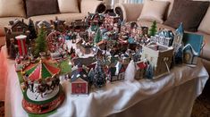 a table topped with lots of christmas decorations and figurines on top of a couch