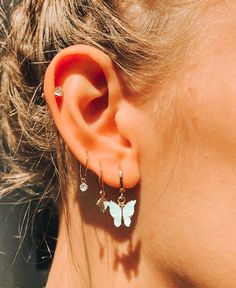 a close up of a person's ear wearing butterfly earrings