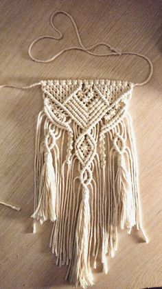 a piece of white yarn with fringes on top of a wooden table next to a string