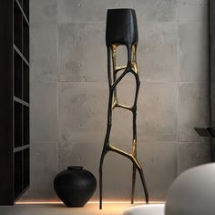 a black and gold stool next to a white vase