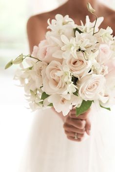 a bride holding a bouquet of white and pink flowers