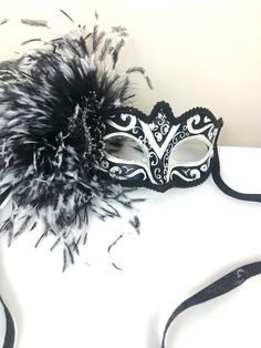 "Feather mask- NYC -Masked ball- New Years Eve- White and black Masquerade Ball- Mardi Gras -Halloween Hello, Made and ready to ship in 1-2 business days. Perfect for a masquerade party, birthday celebration, costume party, New Years Eve celebration or Mardi Gras. These feathers are on the side of a plaster mask that's black and white with some glitter. A beautiful brooch sets it all off! Made with a black sparkle tie. The feathers are about 6\" long. It's on a very comfortable mask...ages 16 an Carnival Evening Masquerade Eye Mask, Gothic Masks For Mardi Gras Theater, Gothic Masks For Theater And Mardi Gras, Halloween Evening Masquerade Mask, Fantasy Black Mask For Masquerade, Black Masquerade Mask For Halloween Evening, Gothic Masquerade Mask For Carnival Evening, Black Venetian Mask For Masquerade, Fantasy Style Masquerade Mask For Mardi Gras