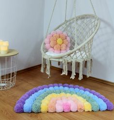 a rainbow rug is on the floor next to a hanging chair with a teddy bear