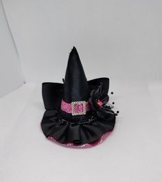 Mini witch hat for babies, girls, adults and pets. Hat size is approximately 3.5 inches wide by 3.5 inches high. Mini hat will be attached to a metal alligator clip, a soft headband or ribbon for pets. Please choose the finish: -5/8 by 16 or 18 inches black soft headband -2.6 inches metal alligator clip -3/8 by 18 or 25 black ribbon (for pets). -There may be slight variation in size -Due to lighting color may vary slightly -All witch hats are made in a smoke free environment -Every hat is handcrafted by me. *Please feel free to contact the seller if you have a question **Mini hats are ready to ship the next business day All mini hats will be shipped in a box. Novelty Brimmed Mini Hats For Costume, Novelty Brimmed Mini Hat For Costumes, Adjustable Brimmed Themed Costume Accessories, Whimsical Adjustable Costume Accessories, Cute Adjustable Headband Costume Accessories, Cute Adjustable Halloween Headband, Adjustable Novelty Top Hat For Halloween, Halloween Costume Hat Accessories, Novelty Adjustable Top Hat For Halloween